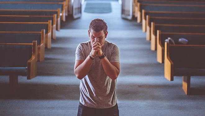 мужчина молится в церкви на коленях